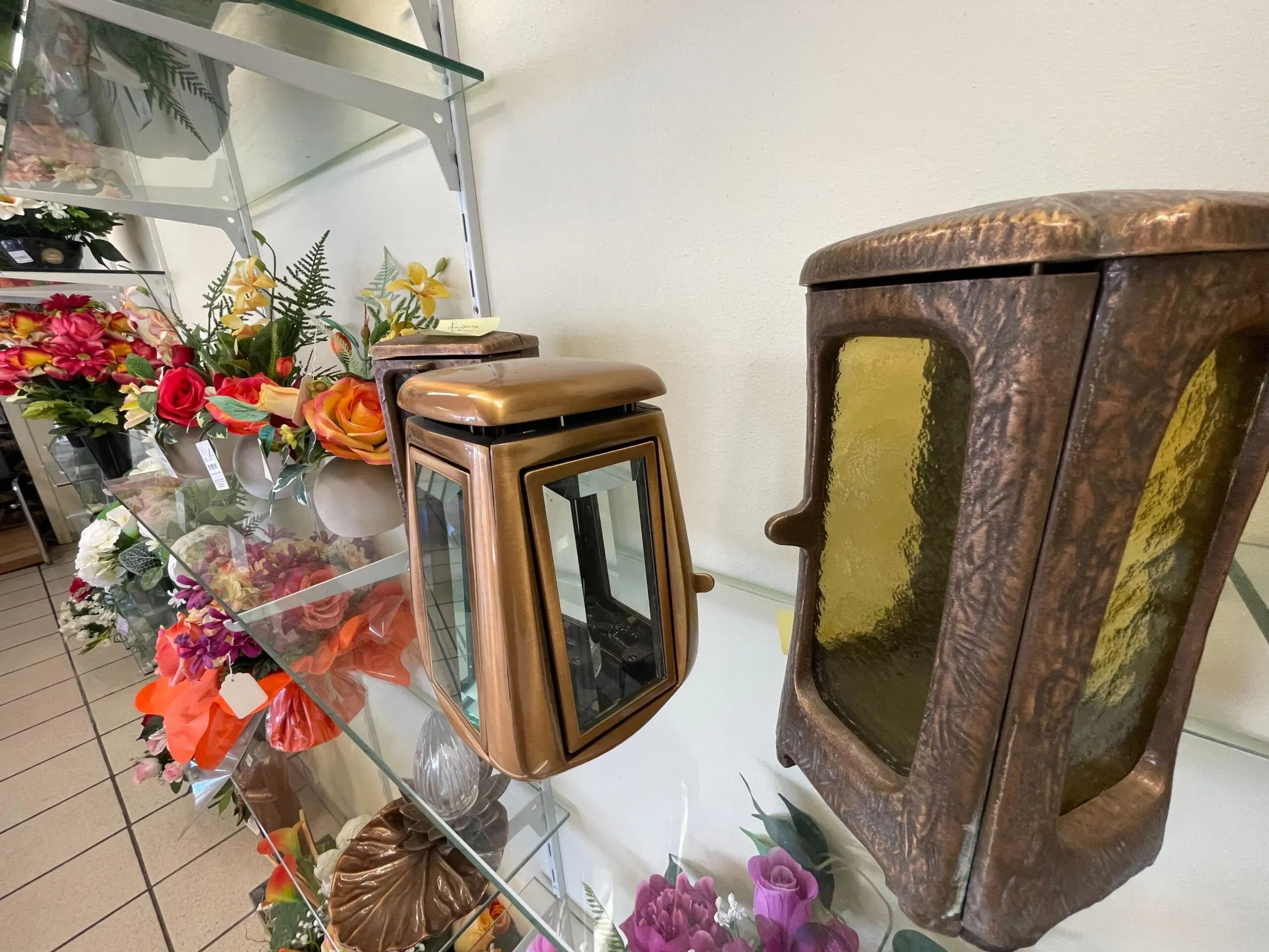 Lanternes funéraires en bronze et verre exposées en magasin sur des étagères