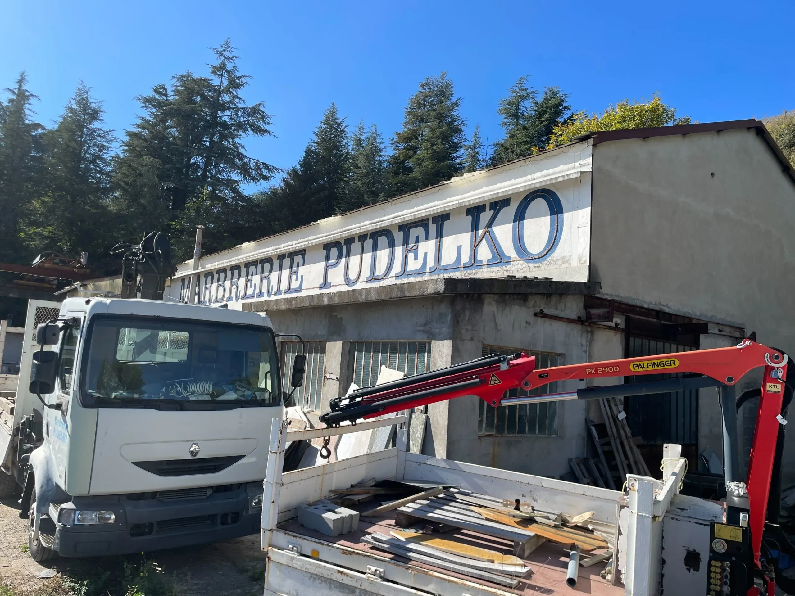 Camion avec grue de manutention stationné devant l'atelier de la Marbrerie Pudelko