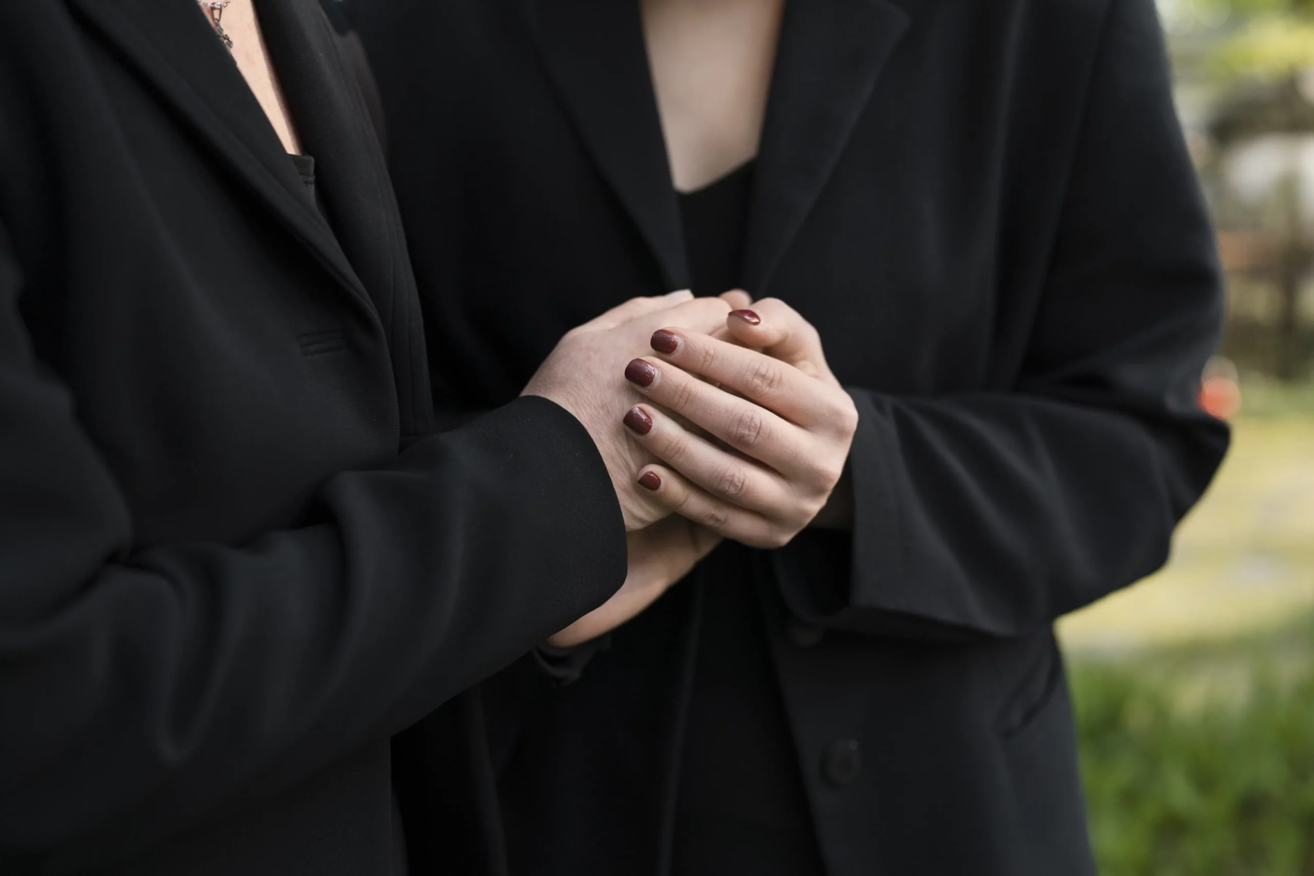 Geste de soutien et réconfort entre deux personnes vêtues de noir lors d'obsèques